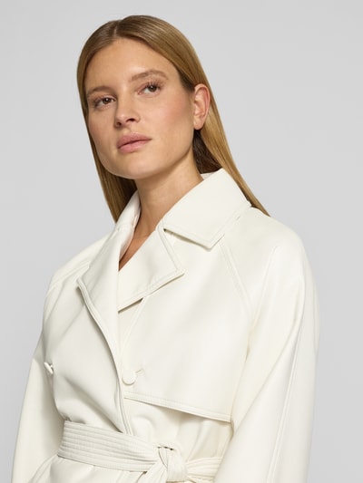 Kobiece modelka nosi Regular Fit Kunstlederjacke mit Bindegürtel Modell 'AISANDI' od HUGO w jednolitym kolorze, gładka tekstura, krój regular fit, kołnierz z klapami, podwójny rząd guzików, pasek, długie rękawy, boczne kieszenie, widok zbliżeniowy na górną część ciała.