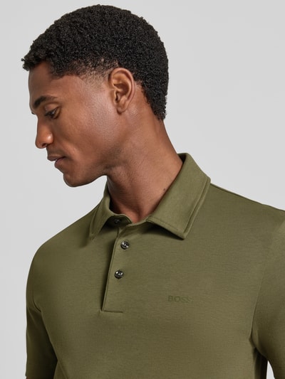 Męski model nosi Regular Fit koszulkę polo z czystej bawełny model 'Palosh 30' od BOSS w kolorze oliwkowym, zbliżenie na górną część ciała. Koszulka polo męska od BOSS.