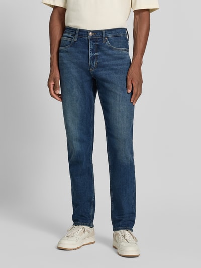Männermodel trägt Tapered Fit Jeans aus Baumwoll-Mix Modell 'David' von Lee, Herren Tapered Fit Jeans, mittleres Blau, Denim-Textur, Ganzkörperansicht von vorne.