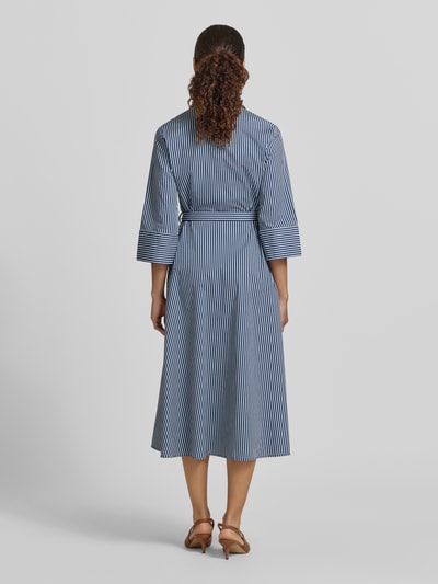 Frauenmodel trägt Hemdblusenkleid mit Bindegürtel und Knopfleiste von Zero im taillierten Schnitt, blau-weiß gestreifter Baumwoll-Mix, Midikleid, Ganzkörperansicht Rückansicht.