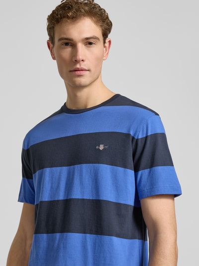 Männermodel trägt Regular Fit T-Shirt mit Logo-Print Modell 'BAR' von Gant, blaue und dunkelblaue Streifen, reine Baumwolle, Nahaufnahme Oberkörper.