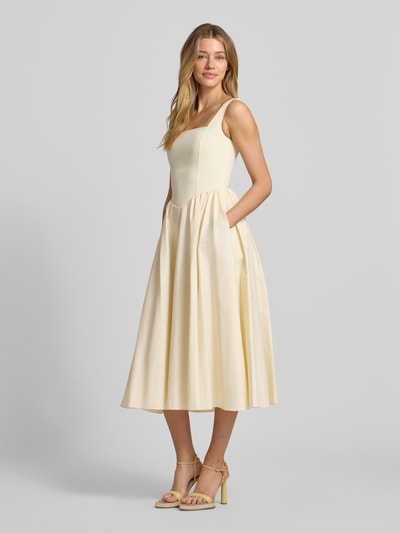 Frauenmodel trägt Cocktailkleid mit rückseitigem Reißverschluss von Jake*s Cocktail aus Baumwoll-Mix mit Stretch-Anteil, A-Linie, Midikleid, sanft glänzender cremefarbener Stoff, glatte Textur, Ganzkörperansicht von vorne. Rückenlänge bei Größe 36: 123 cm, Brustweite: 40 cm.