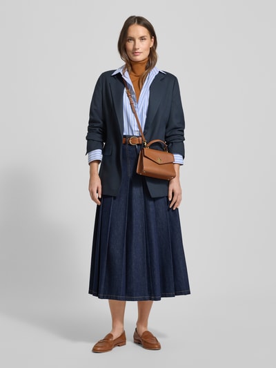 Kobiece modelka nosi Ausgestellter Jeansrock aus reiner Baumwolle Modell 'OVALE' od Weekend Max Mara, kolor denim, długość midi, ozdobne plisy, kontrastowe szwy, pasek i naszywka z logo, widok całej sylwetki z przodu.