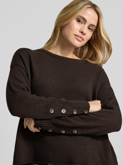 Modelka kobieca nosi sweter z dzianiny z okrągłym dekoltem od Smith and Soul, mieszanka materiałów z domieszką kaszmiru, krój relaxed fit, zrolowany brzeg, długość tyłu w rozmiarze S: 48 cm, długość rękawów w rozmiarze S: 51 cm, kolor brązowy, struktura gładka, widoczne guziki na rękawie, widok z przodu, zbliżenie na górę ciała.