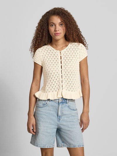 Frauenmodel trägt Stricktop mit Knopfverschluss und Schößchendetail von Review aus Reiner Baumwolle im Regular-Fit, cremefarben, Ganzkörperansicht von vorne.