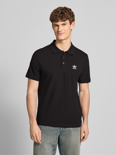 Männermodel trägt Regular Fit Poloshirt mit Logo-Stitching von adidas Originals in Schwarz, reine Baumwolle, Nahaufnahme Oberkörper.