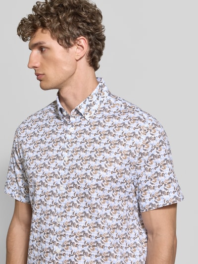 Męski model nosi Slim Fit Freizeithemd mit Button-Down-Kragen von bugatti z bawełny, wzór na całej powierzchni, krój slim fit, kołnierzyk typu button down, długość tyłu w rozmiarze M 76 cm, szerokość ramion w rozmiarze M 46 cm, długość rękawów w rozmiarze M 24 cm, jasne kolory, geometryczny wzór, tekstura gładka, ujęcie: Nahaufnahme Oberkörper