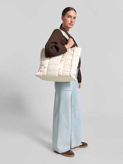 Frauenmodel trägt Handtasche in Stepp-Optik Modell 'Best Buddy' von Hey Marly in Beige, Hauptfach mit Reißverschluss, Trageriemen mit Logo-Detail, Ganzkörperansicht von vorne.