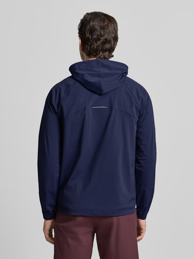 Männermodel trägt Regular Fit Jacke mit Logo-Print von Fabletics in Dunkelblau, elastischer Material-Mix, Kapuze, Ganzkörperansicht Rückansicht.