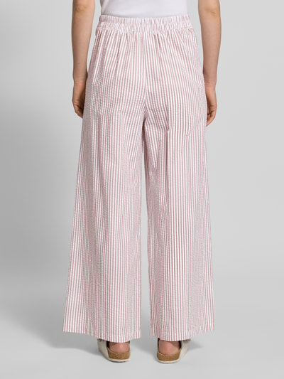 Männermodel trägt Wide Leg Hose mit elastischem Bund von Apricot aus bawełna, wzór na całej powierzchni, szerokość w rozmiarze S: 37 cm, długość wewnętrzna nogawki S: 73 cm, spodnie z szerokimi nogawkami, widok całej sylwetki z tyłu
