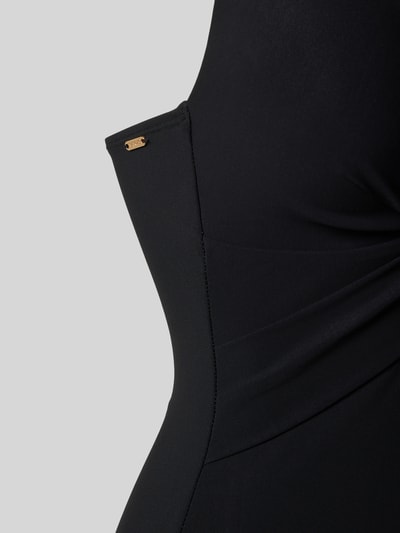 Frauenmodel trägt Badeanzug mit tiefem V-Ausschnitt Modell 'SOLID' von Barts im schwarzen Material-Mix mit Stretch-Anteil, Nahaufnahme Oberkörper.