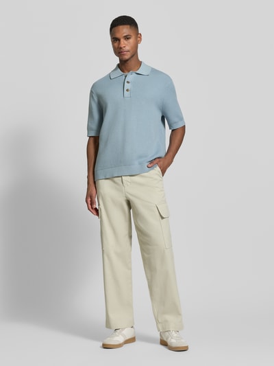 Männermodel trägt Relaxed Fit Poloshirt aus reiner Baumwolle Modell 'DANE' von SELECTED HOMME in Hellblau, Strickoptik, Ganzkörperansicht von vorne.