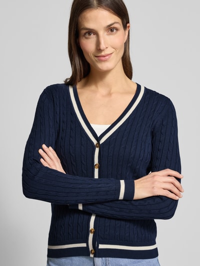 Vrouwenmodel draagt Strickjacke mit V-Ausschnitt van Christian Berg Woman in donkerblauw, katoenmix, regular fit, geribde randen, knoopsluiting, V-hals, borstlengte bij maat S 58 cm, mouwlengte 66 cm, detailopname bovenlichaam.