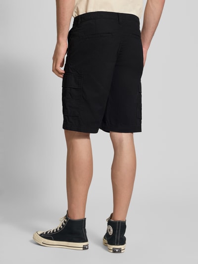 Männermodel trägt Shorts mit Cargotaschen Modell 'COLE MATTY' von Jack & Jones aus reiner Baumwolle, Regular-Fit, schwarze Farbe, Ganzkörperansicht Rückansicht.