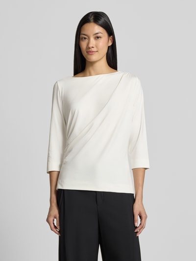 Frauenmodel trägt Regular Fit T-Shirt mit U-Boot-Ausschnitt von s.Oliver BLACK LABEL in Creme mit glatter Textur und schwarzen weiten Hosen, Ganzkörperansicht von vorne.