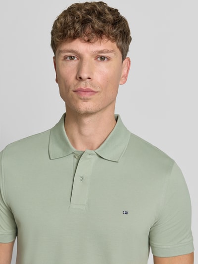 Męski model nosi Regular Fit Poloshirt mit Stitching od Christian Berg Men, jasna zieleń, bawełna, hafty, listwa guzikowa, długość tyłu 64 cm w rozmiarze M, koszulka polo, bawełna, krój regular fit, hafty. Nahaufnahme Oberkörper.