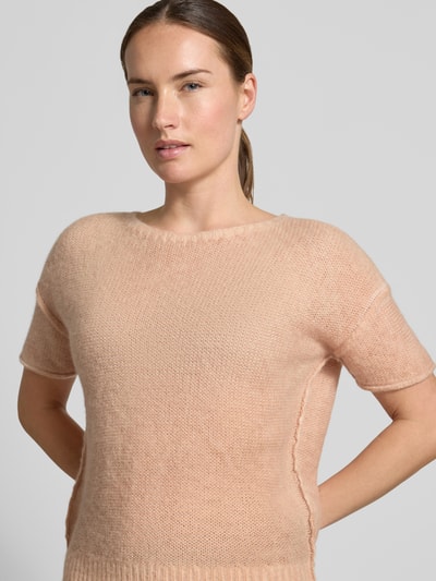 Frauenmodel trägt Strickpullover mit Alpaka-Anteil von Luisa Cerano in zartem Pfirsichton, Ziernähte, gerader Schnitt, Nahaufnahme Oberkörper.