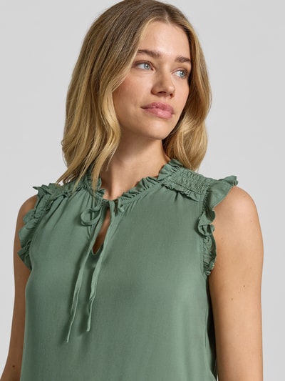 Kobieta prezentuje Regular Fit Blusentop aus reiner Viskose Modell 'ALBA' von Vero Moda, efekt: jednolity kolor, kołnierz z falbanami, wiązany detal, falbany, dekolt w serek, bez rękawów, materiał: wiskoza. Zbliżenie na górną część ciała z przodu.
