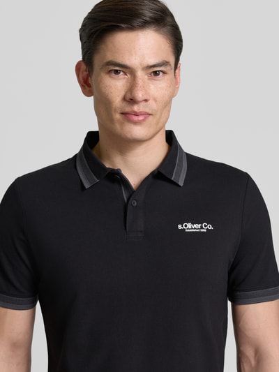 Männermodel trägt Regular Fit Poloshirt aus Baumwoll-Mix von s.Oliver RED LABEL, schwarz, kurzarm, Label Print, Nahaufnahme Oberkörper.
