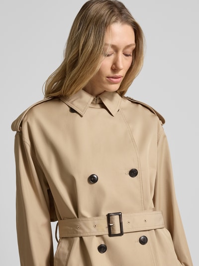 Modelka kobieca nosi Regular Fit Trenchcoat aus reiner Baumwolle od Tommy Hilfiger, beżowy twill, długie rękawy, pasek w talii, zbliżenie na górę ciała z przodu.