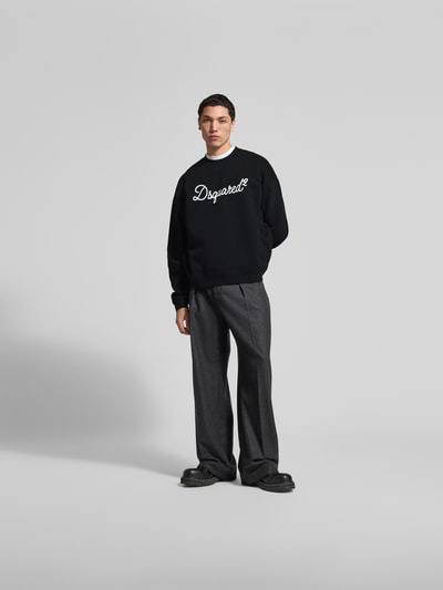 Männermodel trägt Sweatshirt aus reiner Baumwolle von Dsquared2 in Schwarz mit Label-Detail, Relaxed-Fit, elastische Abschlüsse, Ganzkörperansicht von vorne.