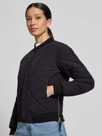 Frauenmodel trägt Steppjacke mit Knopfleiste Modell 'ANGE2' von khujo in Schwarz, Regular-Fit, Stehkragen, Ganzkörperansicht von vorne. Rückenlänge bei Größe S 59 cm, Schulterbreite 36 cm, Brustweite 46 cm, Ärmellänge 61 cm.