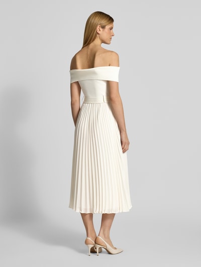 Frauenmodel trägt Cocktailkleid mit Carmen-Ausschnitt Modell 'Capri' von Forever New, cremefarben, plissierter Rock, taillierter Schnitt, Ganzkörperansicht Rückansicht.