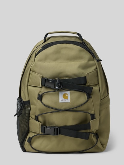 Produktfoto, Rucksack mit Label-Detail Modell 'KICKFLIP' von Carhartt Work In Progress in Oliv mit Hauptfach, Reißverschluss, Tragehenkel, gepolsterten und verstellbaren Schulterriemen, Breite 34 cm, Länge 45 cm, Tiefe 20 cm, Länge Schulterriemen 70 cm, robuste Textur.