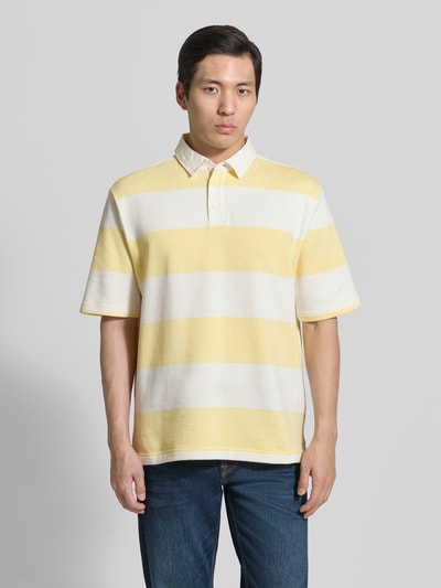 Männermodel trägt Relaxed Fit Poloshirt im Allover-Look von MCNEAL aus Baumwoll-Mix mit Knopfleiste, gelb-weiß gestreift, Ganzkörperansicht von vorne. Rückenlänge bei Größe M: 70 cm.