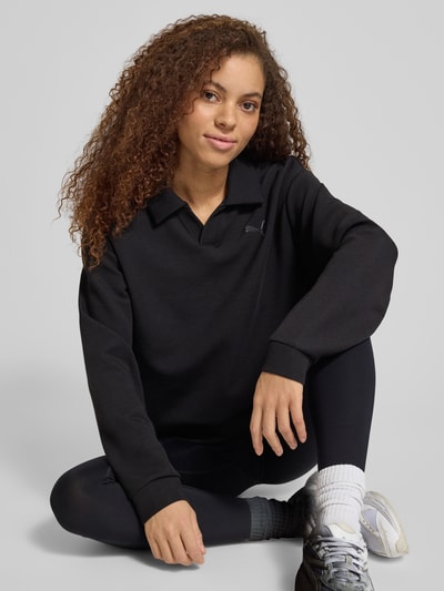Frauenmodel trägt Relaxed Fit Poloshirt mit Lyocell-Anteil von PUMA in Schwarz, Elastischer-Material-Mix, Polo-Kragen, Logo-Detail, Langärmelig, elastische Abschlüsse, Ganzkörperansicht von vorne.