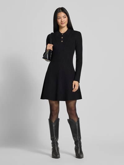 Modelka nosi czarną sukienkę z dzianiny 'Tailliertes Strickkleid aus Viskose-Mix' od Jake*s Collection, gładki materiał, krój slim fit, całkowity widok z przodu.