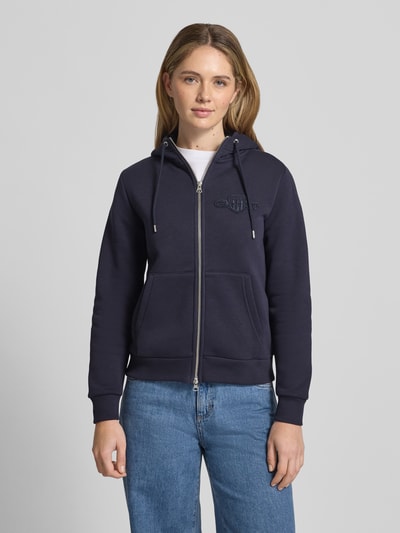 Frauenmodel trägt Sweatjacke mit Zweiwege-Reißverschluss und Label-Stitching von Gant, Baumwoll-Mix, Regular Fit, Kapuze, Känguru-Tasche, Ganzkörperansicht von vorne.