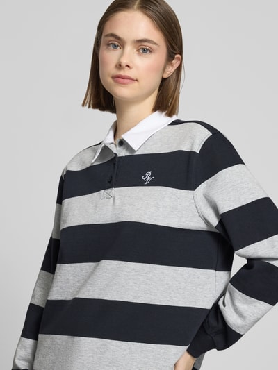 Frauenmodel trägt Polo-Langarmshirt mit Streifen und kontrastiger Knopfleiste von Review, reine Baumwolle, Regular Fit, gesticktes Logo, Nahaufnahme Oberkörper.
