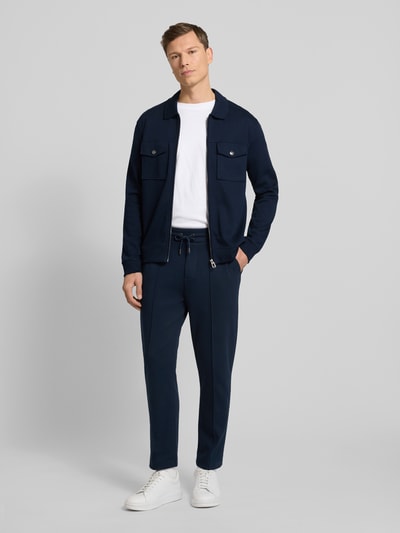 Męski model nosi Sweatjacke mit Reißverschluss Modell 'Tailson' od JOOP! Collection, bawełna, krój regular fit, granat, widok całej sylwetki z przodu.
