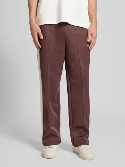 Männermodel trägt Straight Fit Sweatpants mit Logo-Stitching Modell 'Always On' von PUMA PERFORMANCE, brauner Material-Mix, Ziernähte, elastischer Bund, Reißverschlusstaschen, Ganzkörperansicht von vorne.