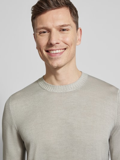 Männermodel trägt Strickpullover aus reiner Schurwolle von GRAN SASSO in Beige, feine Textur, Rundhalsausschnitt, Nahaufnahme Oberkörper.