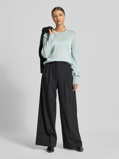 Frauenmodel trägt Regular Fit Pullover aus Viskose-Mix Modell 'Karta' von JOOP! mit Glitzer-Optik, elastische Ärmelabschlüsse, Trompetenärmel und Rundhalsausschnitt, kombiniert mit weitem schwarzem Hose, helle Farben, fließende Textur, Ganzkörperansicht von vorne.