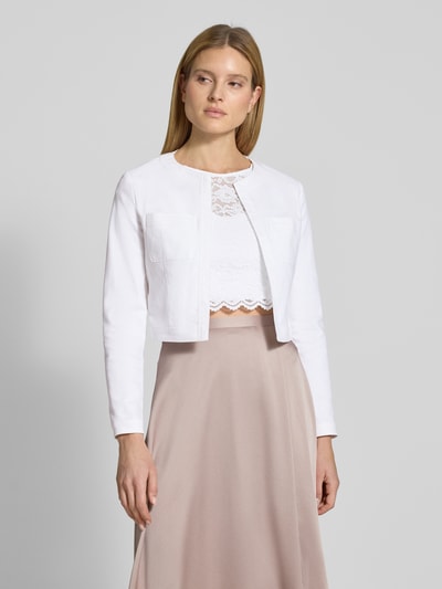 Modelka kobieca nosi Cropped Jacke mit Brusttaschen od SWING, mieszanka bawełny z dodatkiem streczu, krój krótki, otwarty fason, kieszenie na piersi, długość tyłu w rozmiarze 36: 44 cm, ujęcie całej sylwetki z przodu.