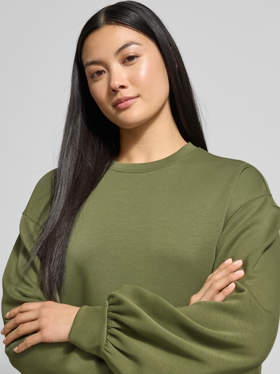 Frauenmodel trägt Oversized Sweatshirt mit gerippten Abschlüssen Modell 'Brionna' von MSCH Copenhagen in Olivgrün, Viskose-Mix mit Stretch-Anteil, Nahaufnahme Oberkörper.