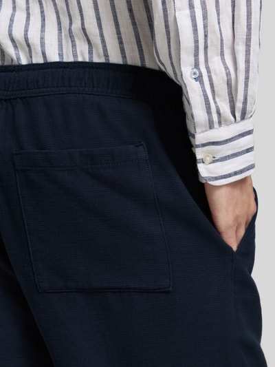 Mężczyzna nosi Shorts aus Baumwolle mit elastischem Bund od JAKE*S STUDIO MEN, granatowy kolor, krój regular fit, detal tylnej kieszeni, zbliżenie na biodro