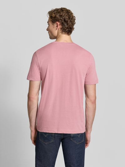 Männermodel trägt Regular Fit T-Shirt aus reiner Baumwolle von Tom Tailor in Rosa, kombiniert mit dunkler Jeans, Ganzkörperansicht Rückansicht. Herren T-Shirt von Tom Tailor.