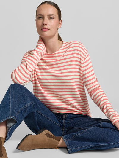 Frauenmodel trägt Longsleeve im Allover-Look mit Rundhalsausschnitt von Closed im Baumwoll-Modal-Mix, relaxed Fit, Streifenmuster in Rosa und Weiß, kombiniert mit blauen Jeans und braunen Stiefeletten, Ganzkörperansicht von vorne.
