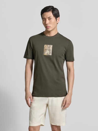 Männermodel trägt Regular Fit T-Shirt mit Logo-Patch von ARMANI EXCHANGE in Olivgrün, reine Baumwolle, Rundhalsausschnitt, Ganzkörperansicht von vorne.