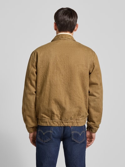 Männermodel trägt Regular Fit Bomberjacke aus reiner Baumwolle van Tommy Hilfiger in effen bruin, denimstructuur, elastische boorden, Ganzkörperansicht Rückansicht.