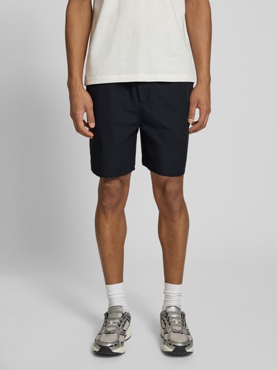 Männermodel trägt Shorts mit elastischem Bund Modell 'Raphael' von Les Deux, Regular Fit, dunkle Farbe, glatte Textur, Ganzkörperansicht von vorne.