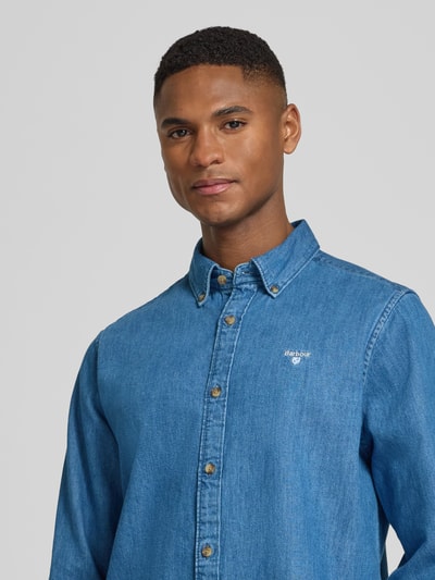 Männermodel trägt Slim Fit Jeanshemd aus reiner Baumwolle von Barbour in Denim-Optik mit Button-Down-Kragen und Label-Stitching, Nahaufnahme Oberkörper.