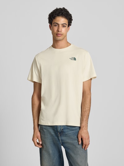 Męski model nosi Relaxed Fit T-Shirt mit Logo-Print von The North Face z bawełny, okrągły dekolt, kremowy kolor, długość tyłu 70 cm, Ganzkörperansicht von vorne.