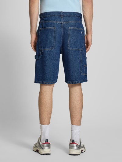 Männermodel trägt Baggy Fit Jeansshorts mit Eingrifftaschen von REVIEW aus Reine Baumwolle, Farbe Blau, Ganzkörperansicht Rückansicht.