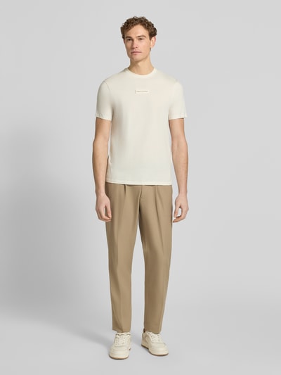 Männermodel trägt T-Shirt mit Label-Detail und Rundhalsausschnitt von ARMANI EXCHANGE, Beige und Weiß, Regular Fit, Obermaterial Baumwolle, Ganzkörperansicht von vorne.