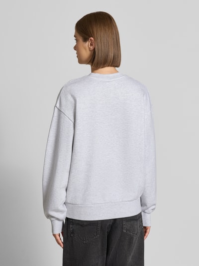 Vrouwenmodel draagt lichtgrijze sweatshirt uit puur katoen Model 'Casey' van Carhartt Work In Progress, losse pasvorm, geribde boorden, rugaanzicht